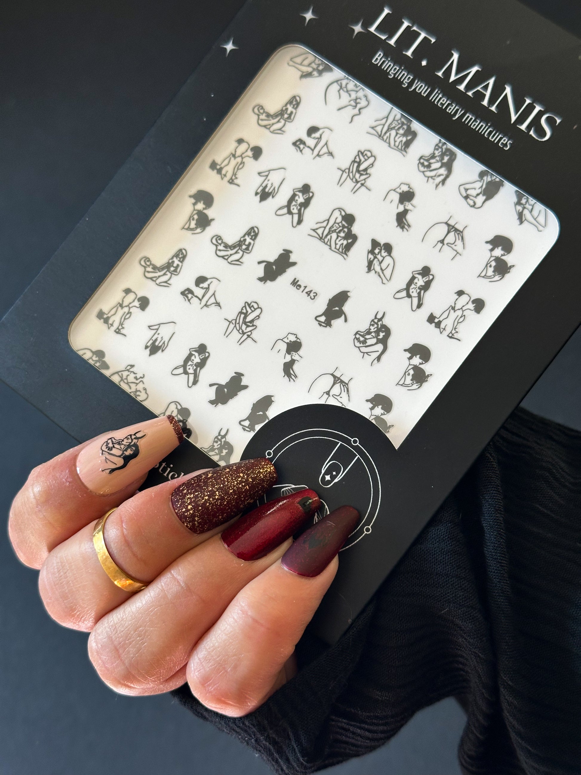 Nail art design sheet by LIT. MANIS held by a hand with painted nails.